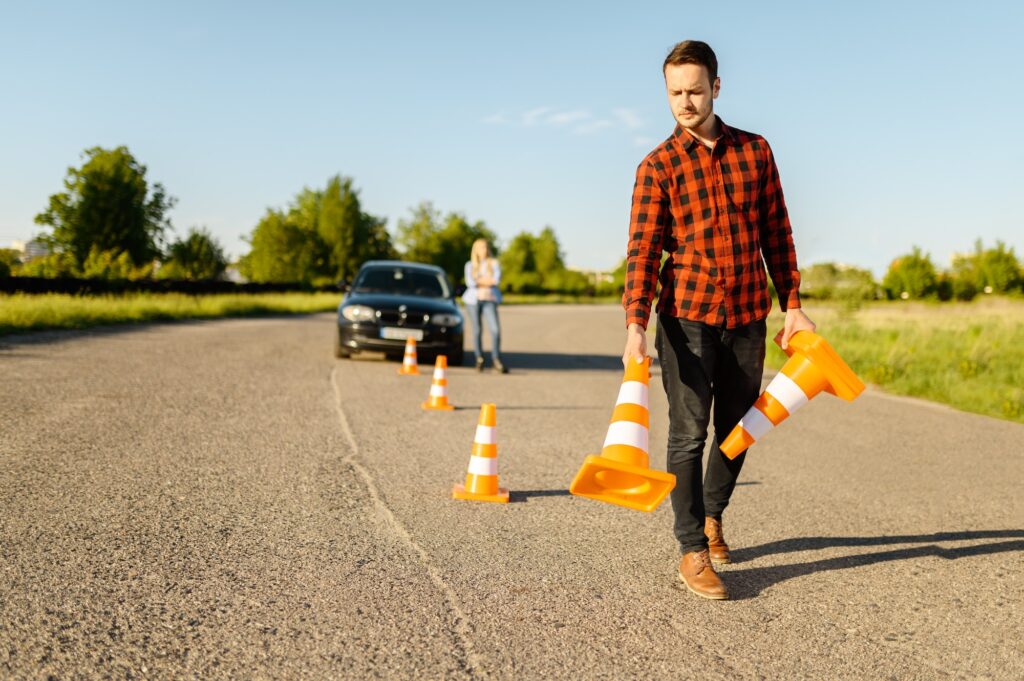 Male instructor puts cones on road, driving school