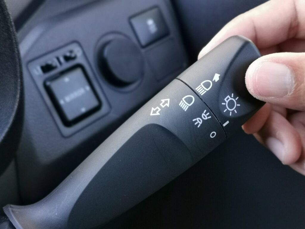 Man turning on car headlamp switch. Car interior details.