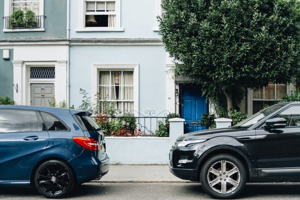 Two parked cars in front of an apartment entrance | Understanding Parallel Parking: What it is and Why is it Important?