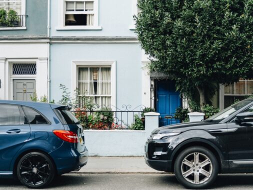 Two parked cars in front of an apartment entrance | Understanding Parallel Parking: What it is and Why is it Important?